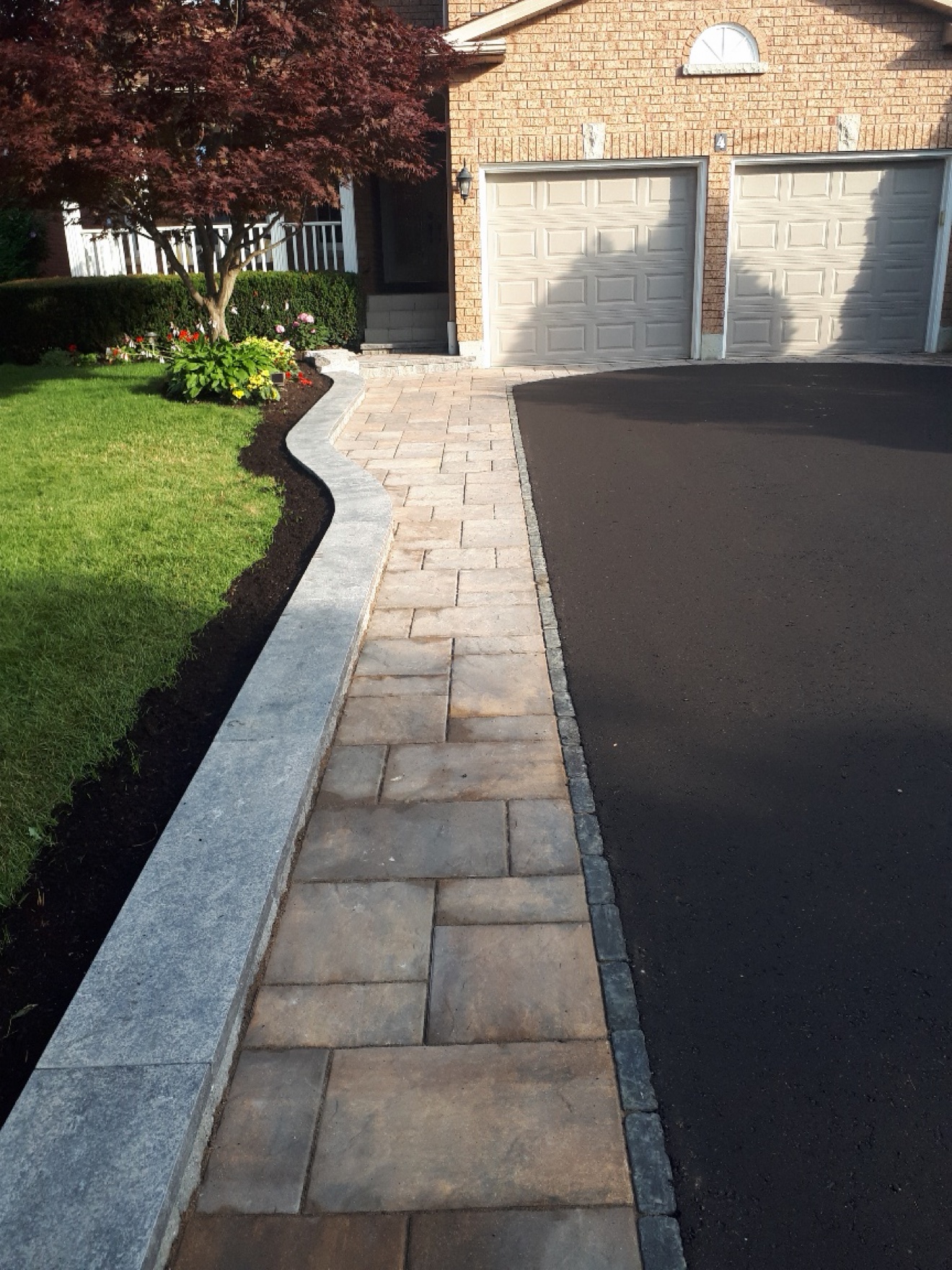 Interlocking paver walkway with curved curb and garden bed by Manulock Construction