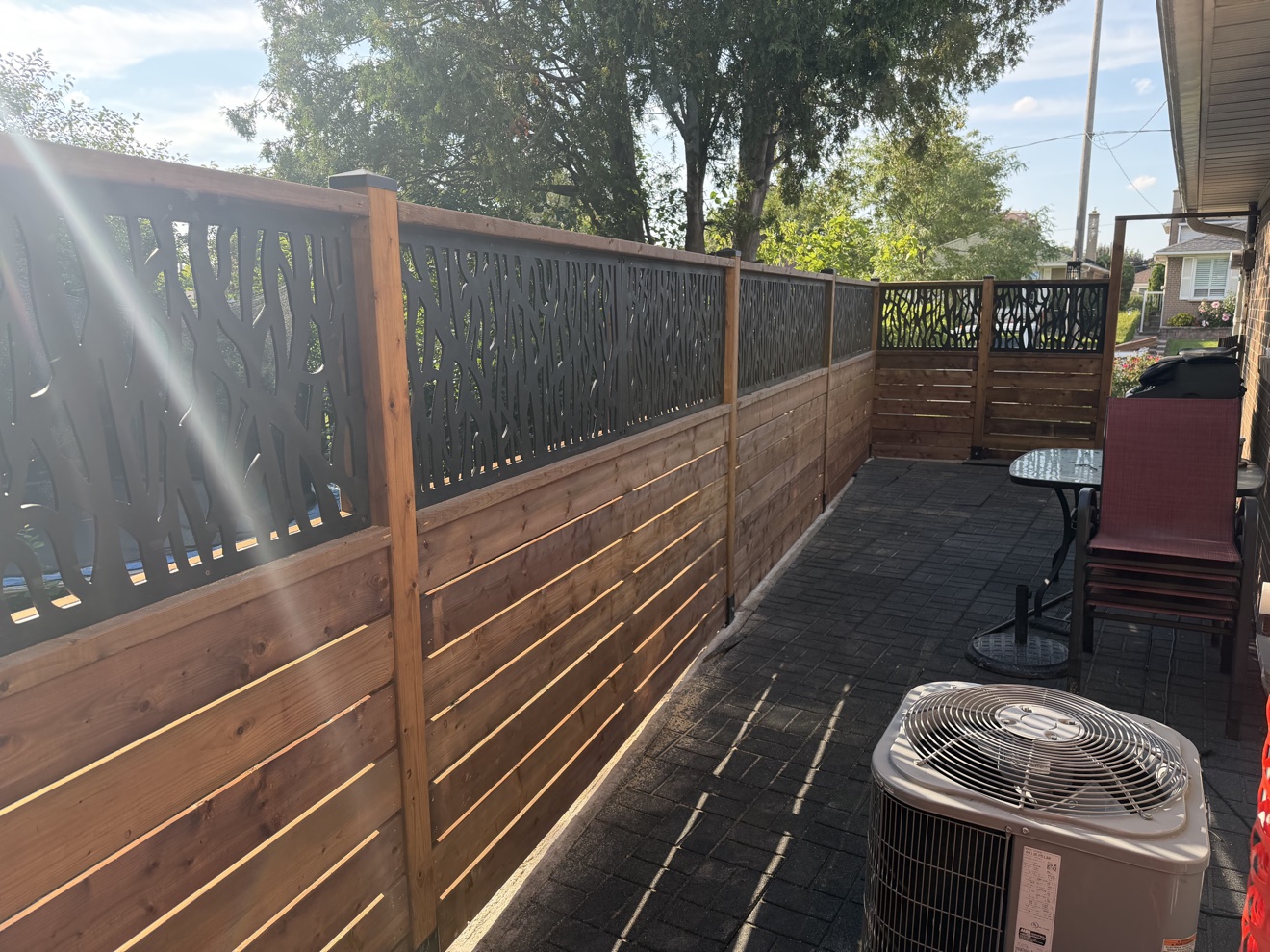 Decorative wooden privacy fence with laser-cut metal panels built by Manulock Construction